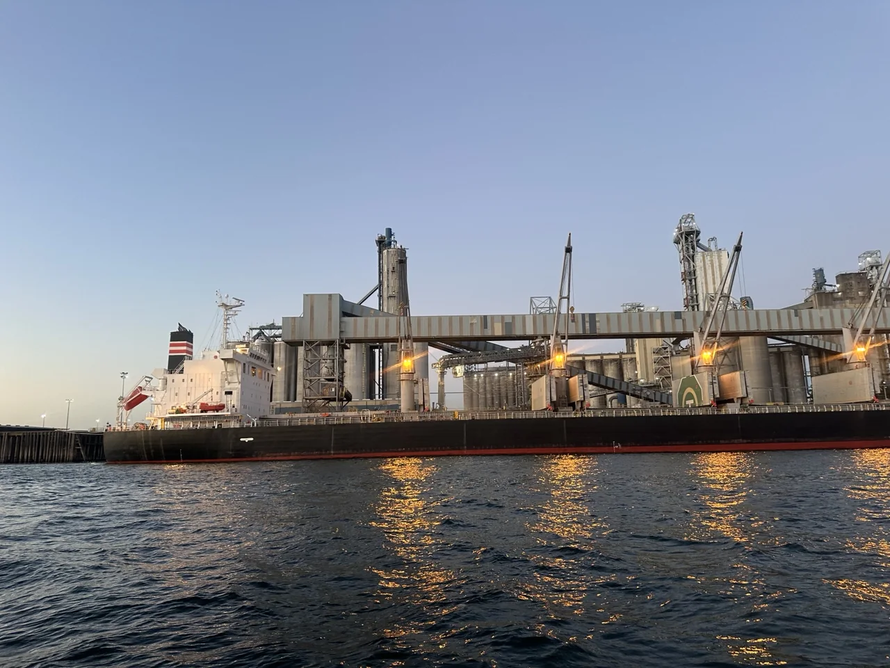 Bulk vessel alongside terminal conveyors and loading infrastructure